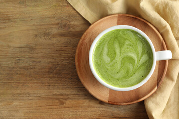 Cup of aromatic matcha latte on wooden table, top view. Space for text