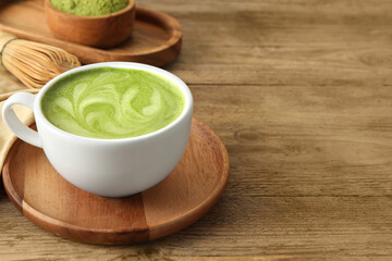 Cup of aromatic matcha latte on wooden table. Space for text