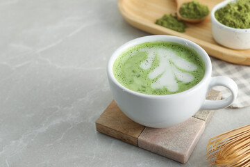 Cup of fresh matcha latte on light grey marble table, closeup. Space for text