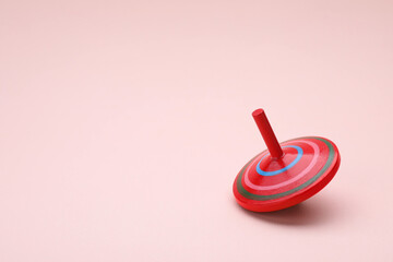 One bright spinning top on beige background, space for text. Toy whirligig
