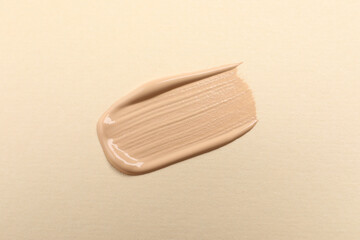 Smear of skin foundation on beige background, top view