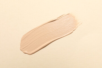 Smear of skin foundation on beige background, top view