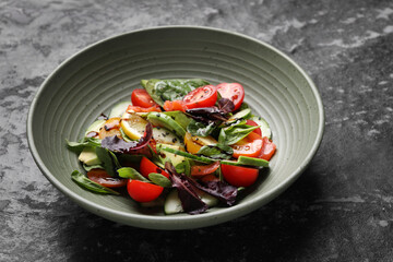 Delicious vegetable salad on black textured table