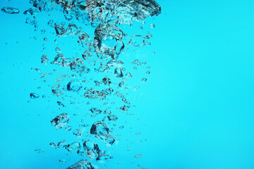 Many air bubbles in water on light blue background, space for text