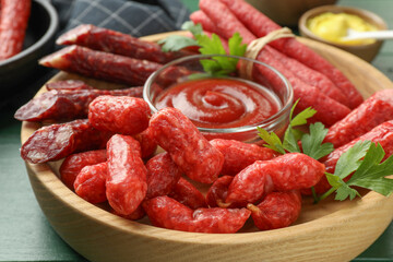 Different thin dry smoked sausages, parsley and ketchup on table, closeup