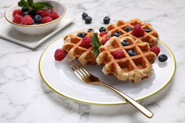 Delicious Belgian waffles with fresh berries and mint on white marble table, closeup