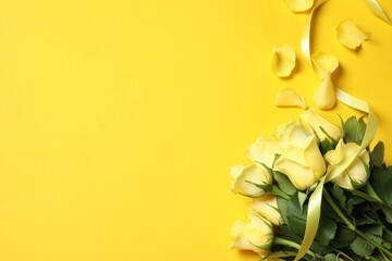 Beautiful roses, petals and ribbon on yellow background, flat lay. Space for text