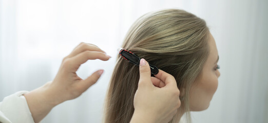 professional hair stylist puts a hairpin in the woman's hair in salon