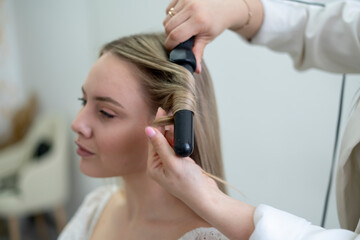 Obraz na płótnie Canvas the expert stylist hairdresser doing work, making beautiful curls