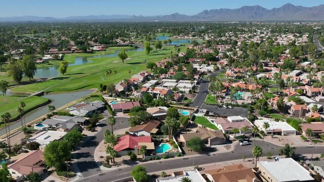 Country club retirement housing development and neighborhood in Scottsdale, Arizona. Southwest USA. Aerial orbit shot above houses and homes with golf course in background.