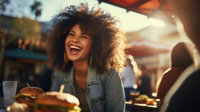 A happy woman eating a burger in an outdoor restaurant as a Breakfast meal craving deal.