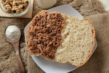 Bread with minced beef and union on a table. With white milk and snack for breakfast