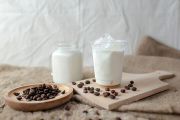 Fresh milk for delicious iced coffee, beans and mint on white wooden table