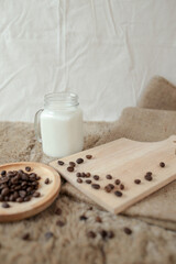 Fresh milk for delicious iced coffee, beans and mint on white wooden table