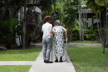 Elderly woman exercise walking in backyard with daughter.