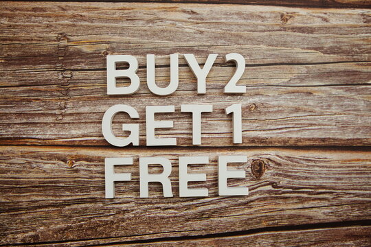 Buy 2 Get 1 Free alphabet letters on wooden background