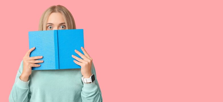 Shocked young woman with book on pink background with space for text