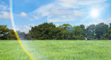 緑の丘、土手、高台さわやかな青空と緑の草原・芝生の背景壁紙　アウトドア・スポーツ・行楽・レジャー・旅行・遠足・運動会の背景　晴天の太陽と虹色のレンズフレア・ゴースト