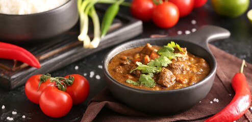 Frying pan with tasty curry on dark background