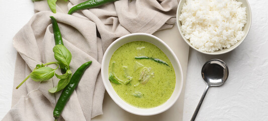 Bowl of tasty green chicken curry and ingredients on light background