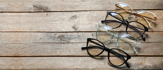 Different stylish eyeglasses on wooden background with space for text