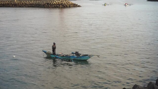 A fisherman is fishing using a traditional boat.