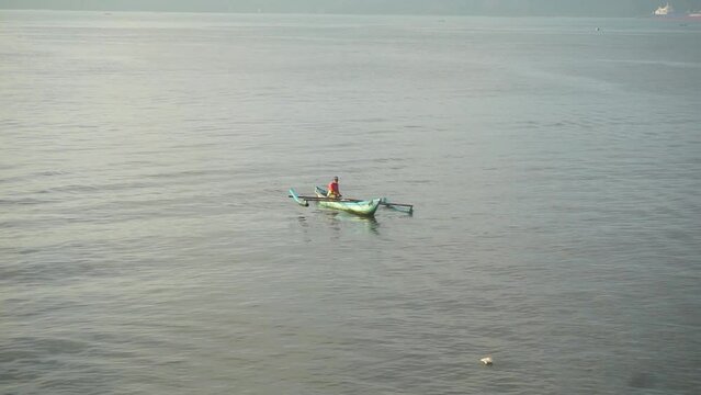A fisherman is fishing using a traditional boat.