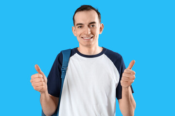 Male student showing thumbs-up on blue background