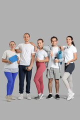 Group of sporty young people with equipment on grey background