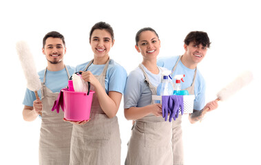 Young janitors with cleaning supplies on white background