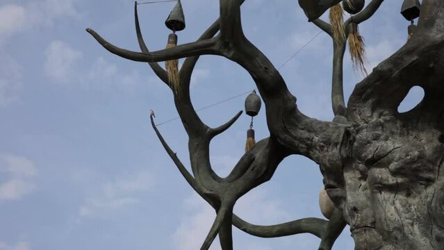Baikal Lake. Olkhon Island.  Video of bird sitting on branch of sculpture of old tree with bells of Baikal Keeper against blue sky