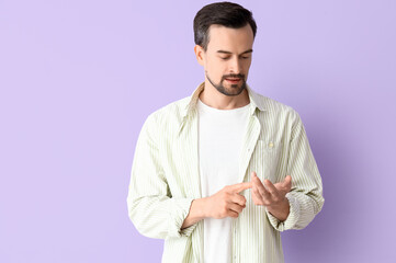 Handsome man counting on lilac background