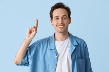 Young man pointing at something on blue background
