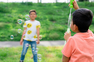 Two unrecognizable children playing in the park with soap bubbles. 