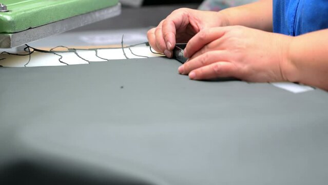 Employee cuts artificial leather with press machine