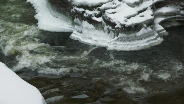 Freezing mountain river flowing by ice covered rocks at winter, Ausable Chasm