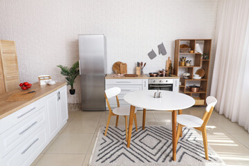 Interior of light kitchen with white counters, fridge and dining table