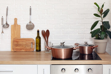 Wooden counters with cutting boards, utensils, houseplant and electric stove in modern kitchen