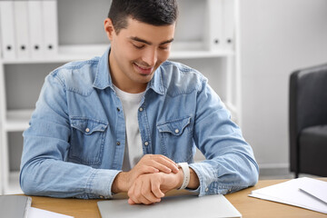 Young man looking at smartwatch in office