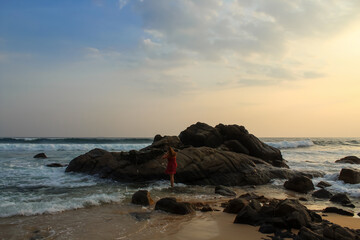 The girl wearing the red dress walking towards the huge granite rocks, Sri Lanka