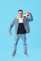 Young man with soccer ball on blue background