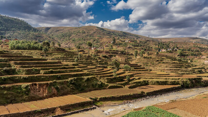 Terraces of rice fields on the mountain slope descend to the river. Rural houses are visible in the...