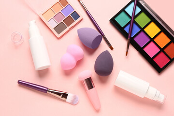 Composition with different cosmetic products and makeup accessories on pink background