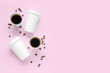 Composition with takeaway paper cups of tasty coffee and beans on pink background