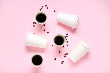 Composition with takeaway paper cups of tasty coffee and beans on pink background