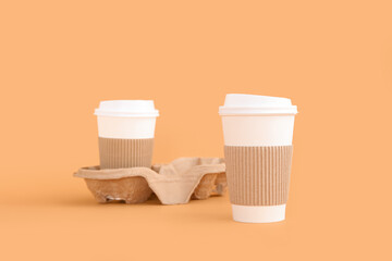 Takeaway paper cups with holder on beige background