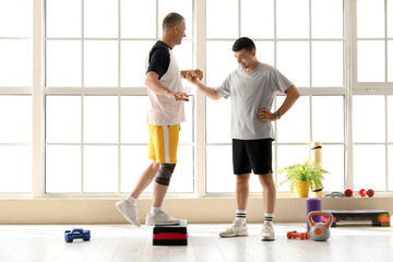 Mature man training with stepper and therapist in rehabilitation center