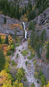Vertical view of Upper Falls in Provo Canyon during Fall color flying backwards revealing the colorful leaves.