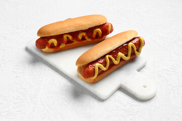 Board with tasty hot dogs on white background