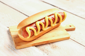 Board with tasty hot dog on white wooden background